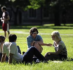 Students seated in the grass on campus 