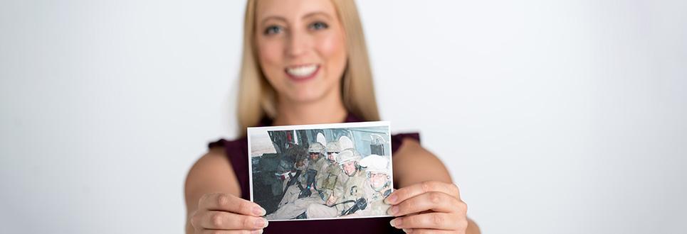 Veteran holding a photo of herself when she was deployed