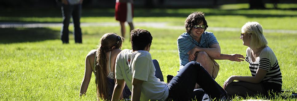 Students seated in the grass on campus 